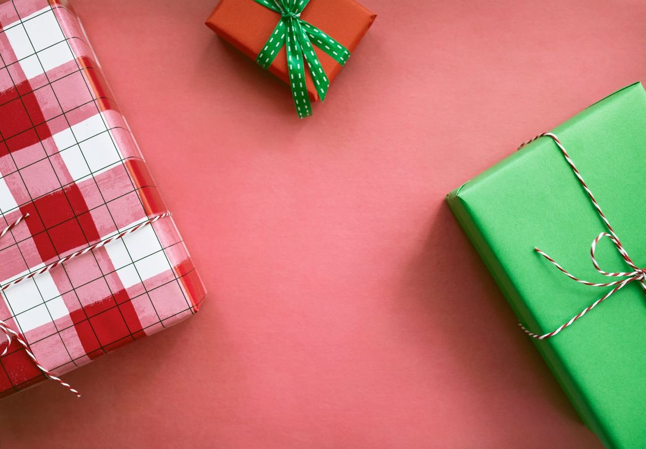 Colorful gift boxes with festive wrapping on a red background, perfect for holiday themes.