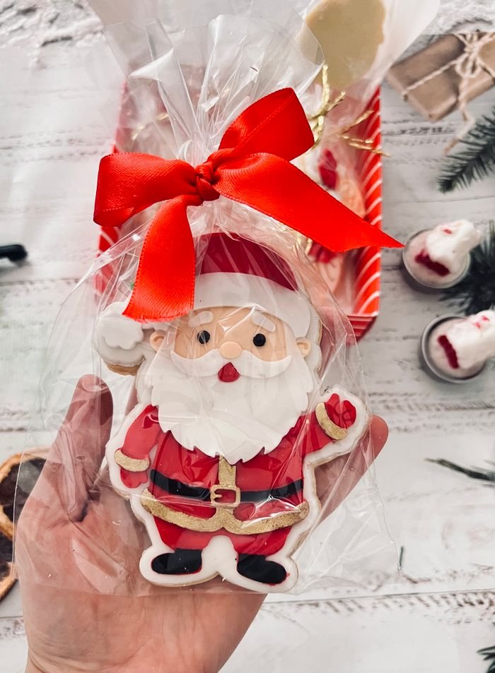 Decorative Santa Claus cookie wrapped as a holiday gift with a red bow, perfect for Christmas.
