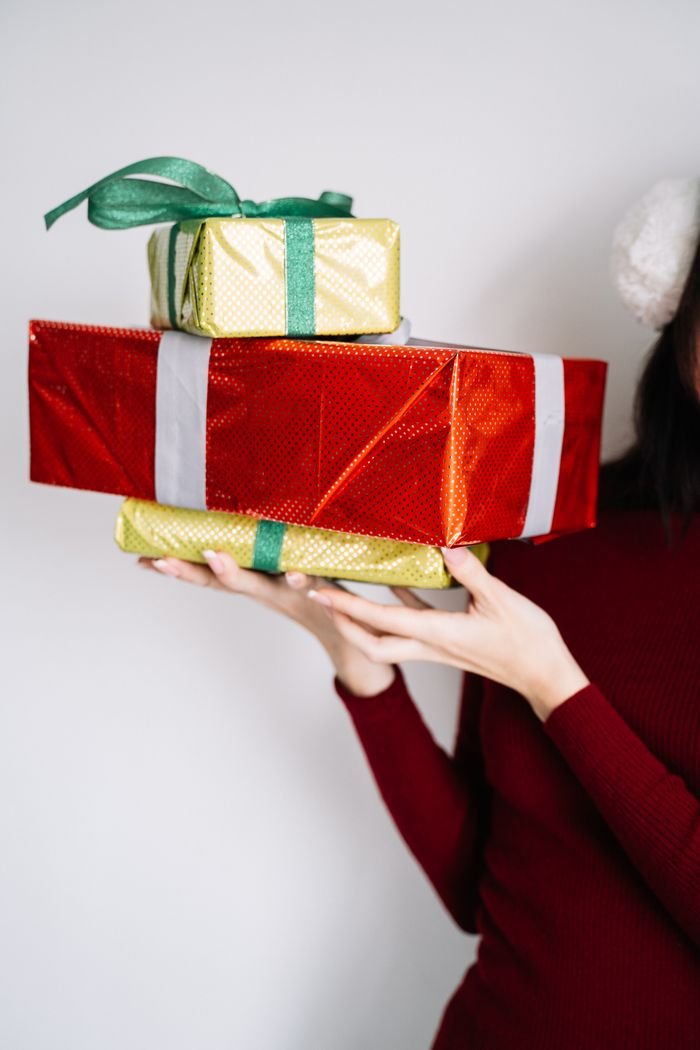 Home Close-up of hands holding wrapped holiday gifts in vibrant colors.