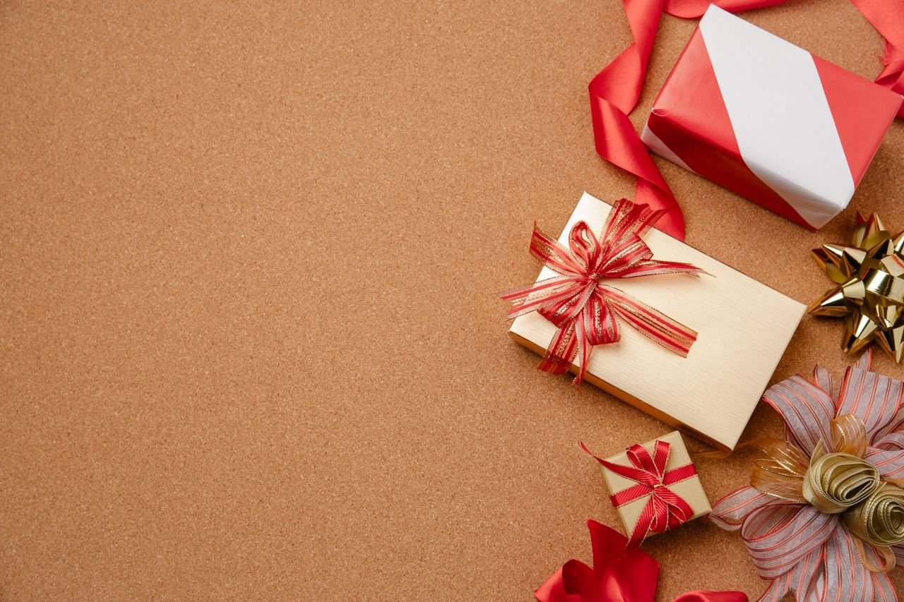 Top view of festive gift boxes with ribbons on brown background, perfect for holiday themes.